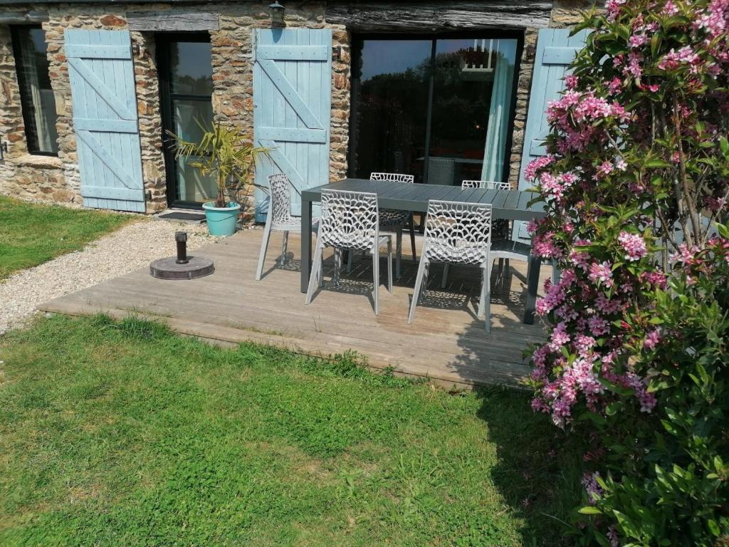een patio met een tafel, stoelen en bloemen bij Ty Maez - Calme et confort à Sarzeau- Les Gites de Rhuys in Sarzeau