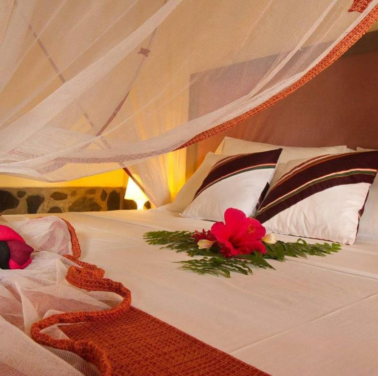 a white bed with a red flower on it at Madiro hôtel in Nosy Be