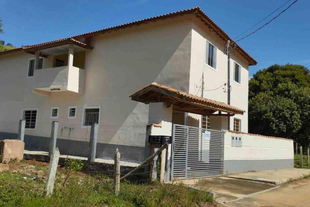 a white house with a fence in front of it at Apto. em Conceição dos Ouros MG in Conceição dos Ouros
