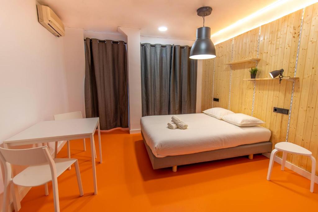 a small room with a bed and a table and chairs at Koala Hostel Mercado in Alicante