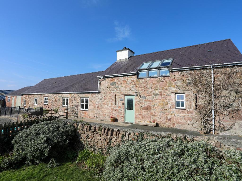 a brick house with a black roof at Tan Twr - Chellow Cottage in Dwyran