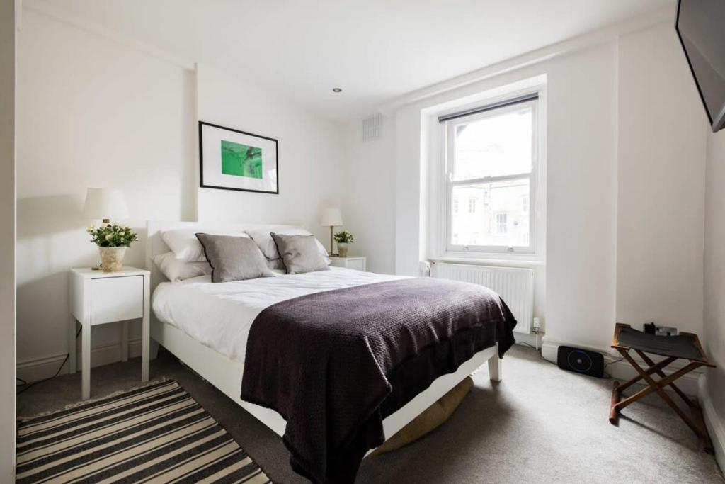 Un dormitorio blanco con una cama grande y una ventana en Modern 3-bed Duplex Apartment in Fitzrovia near Oxford Street, en Londres