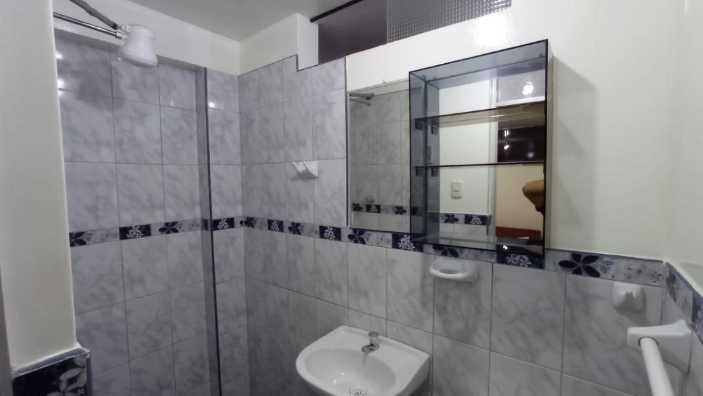 uma casa de banho com um lavatório e um espelho em Hospedaje El Manantial em Oxapampa