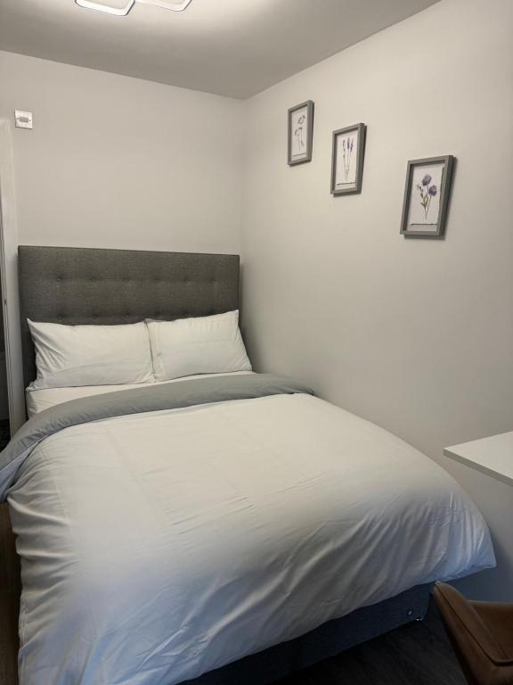 a white bed in a bedroom with three pictures on the wall at Private En-suite in Birmingham