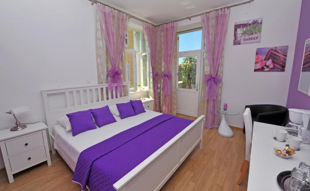 a bedroom with a bed with purple sheets and a window at Luxury Rooms Nirvana in Split