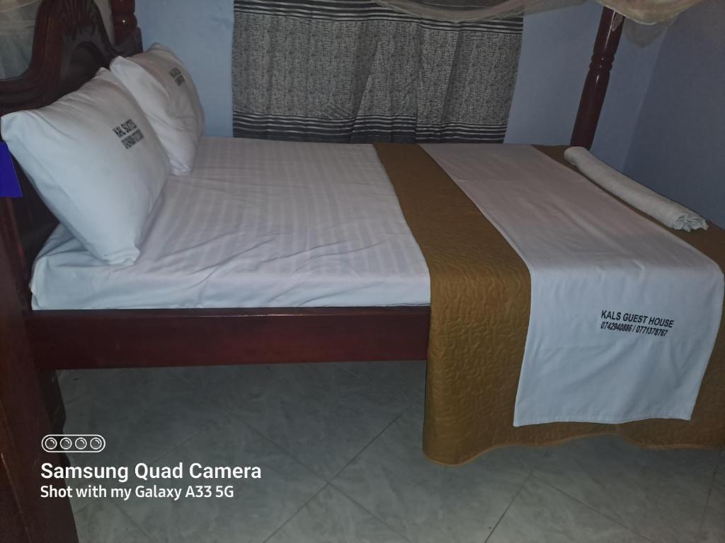 a bed with white sheets and a wooden frame at Kal Era Suites in Mbarara