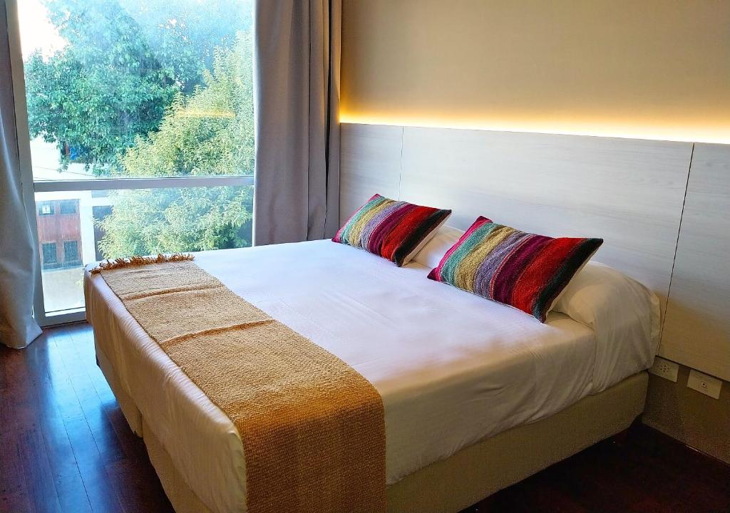 a bed with two pillows in a room with a window at Roomie Salta by DOT Suites in Salta