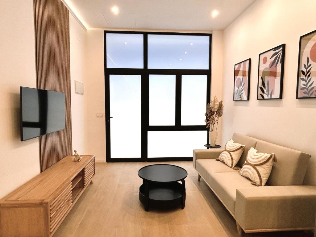 ein Wohnzimmer mit einem Sofa und einem TV in der Unterkunft Estudio a Estrenar a metros de los Jardines del Turia in Valencia