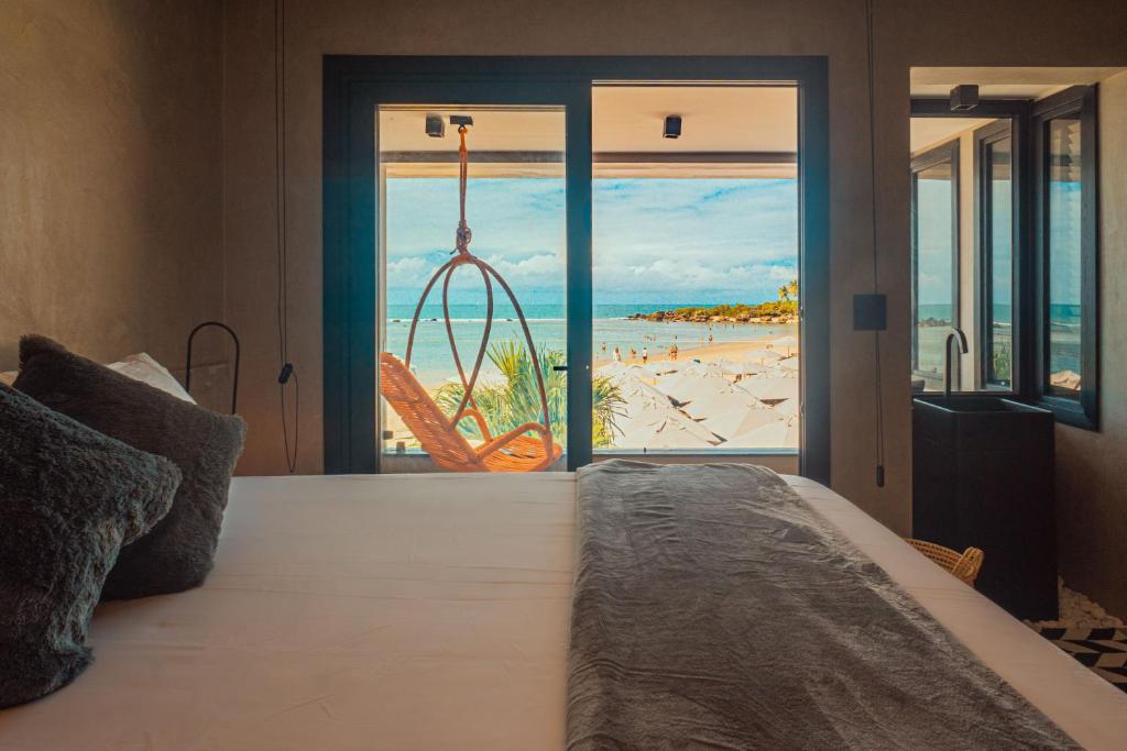 a bedroom with a bed with a view of a beach at Marilyn Pousada Morro in Morro de São Paulo