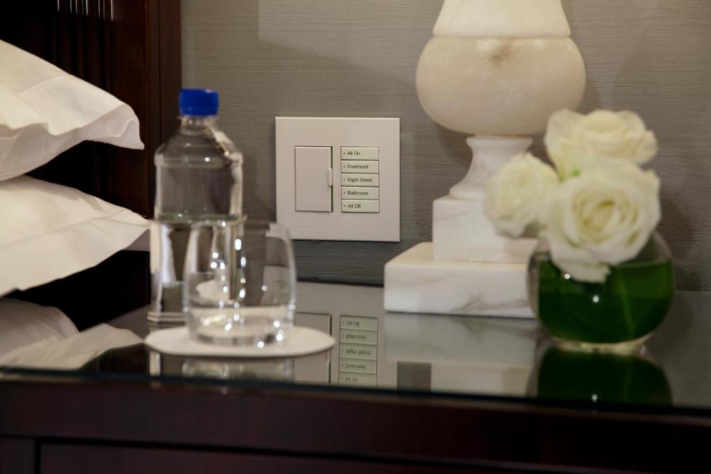 a glass table with a bottle and a vase with flowers at Trump International New York in New York