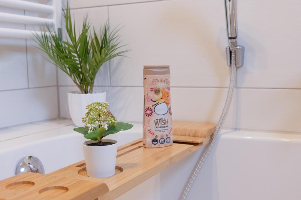 a shelf in a bathroom with two plants and a bath tub at Apartment Sängerstadt Flat Peter in Finsterwalde