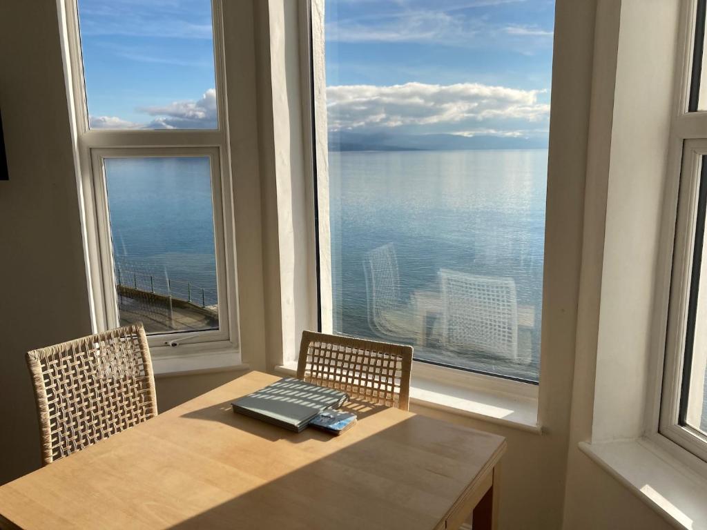 a table with a laptop on it in front of a window at Marine Terrace Apartments in Criccieth