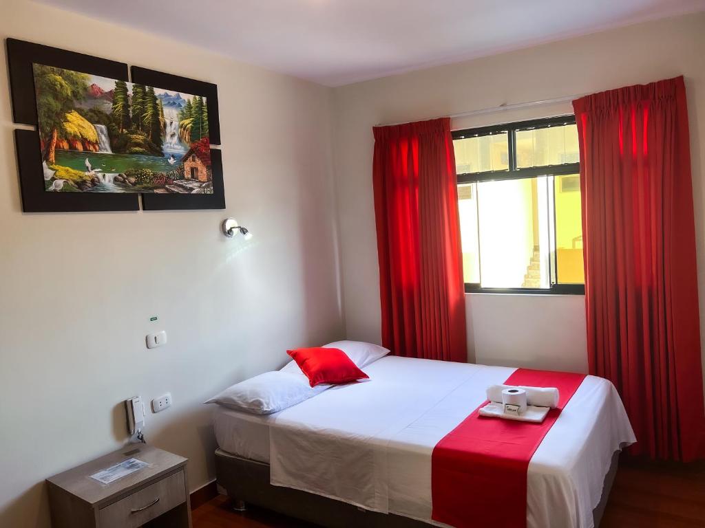 1 dormitorio con 1 cama y una ventana con cortinas rojas en Residencial Marina House en Tarapoto