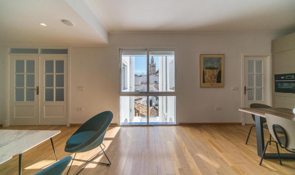 une chambre vide avec une table, des chaises et une fenêtre dans l'établissement REY DE SEVILLA FLATS - Arenal, à Séville