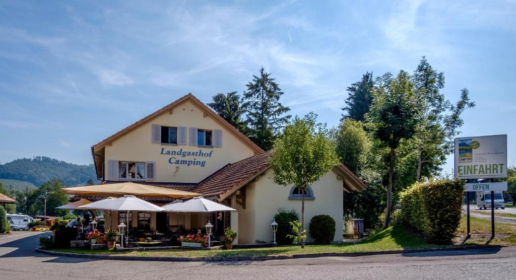 un bâtiment avec des parapluies devant lui dans l'établissement Landgasthof Camping, à Wagenhausen