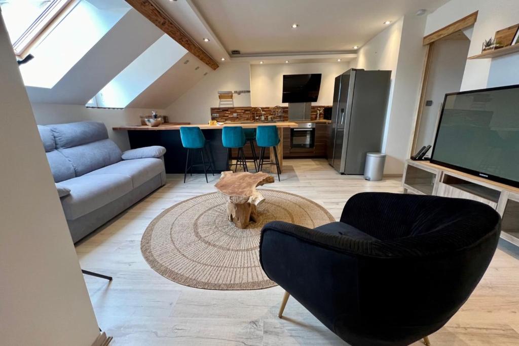 een woonkamer met een bank en stoelen en een tv bij Quiet luxury nest in the heart of Gérardmer in Gérardmer