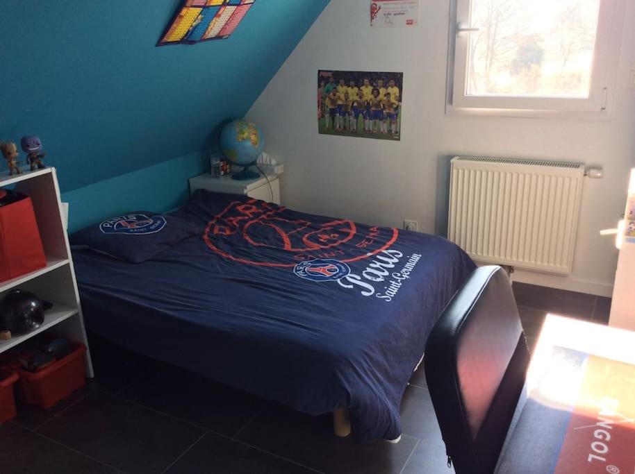 uma cama num quarto com uma parede azul em Plages débarquements .DDay. Près de Caen em Verson