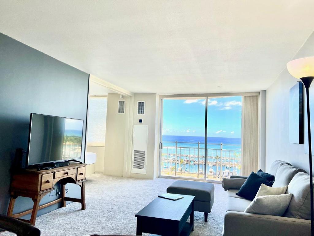 a living room with a flat screen tv and a large window at Ilikai Marina 1386 in Honolulu