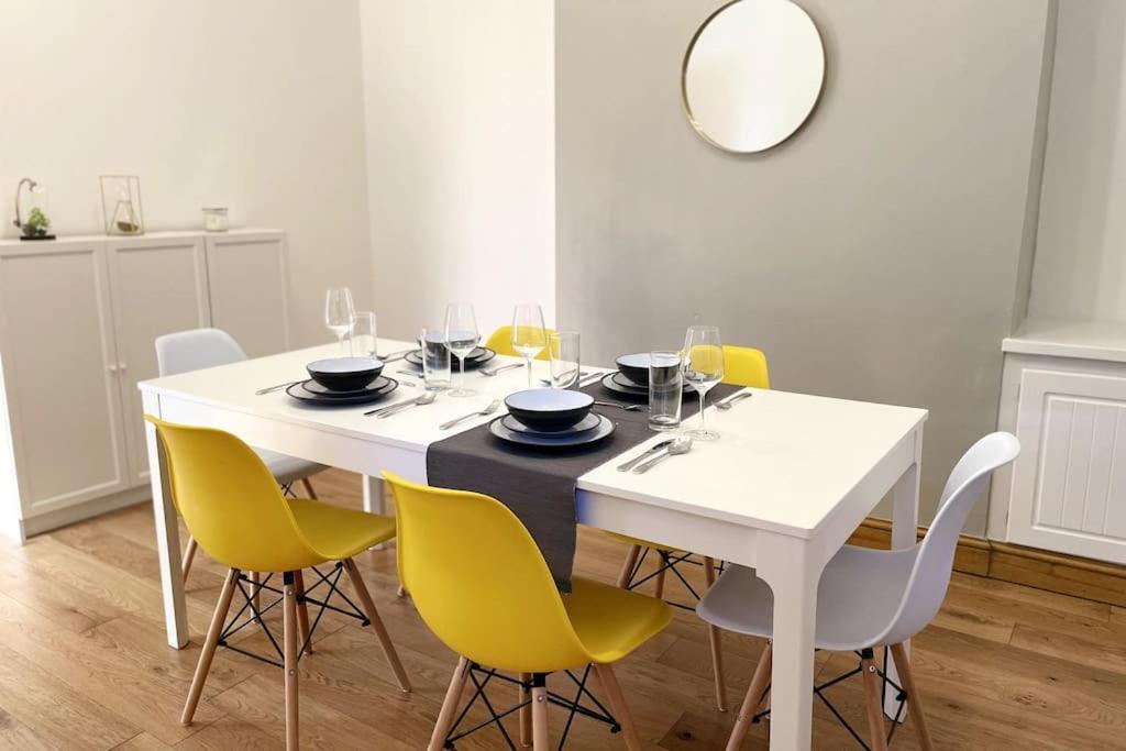 a dining room with a white table and yellow chairs at Free Parking - Near Coop Live, Etihad - Comfy 3-Bed House in Manchester in Manchester