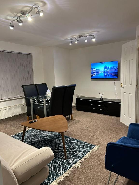 a living room with chairs and a table and a tv at Cosy 2 Bedroom Apartment with Parking by Cloud Suites in Manchester