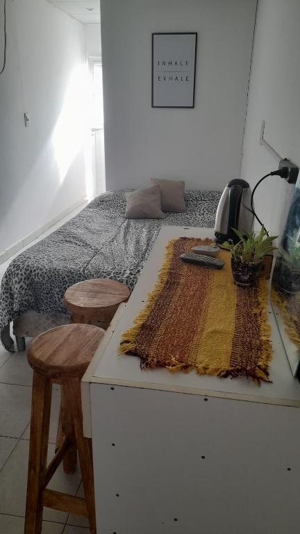 een slaapkamer met een bed met 2 krukken en een tafel bij Hospedaje Luna in Chajarí