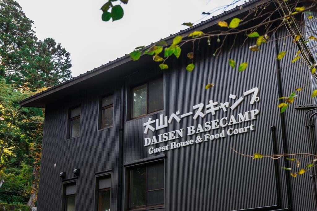 Ein schwarzes Gebäude mit einem Schild an der Seite. in der Unterkunft 大山ベースキャンプ（Daisen Basecamp） in Daisen