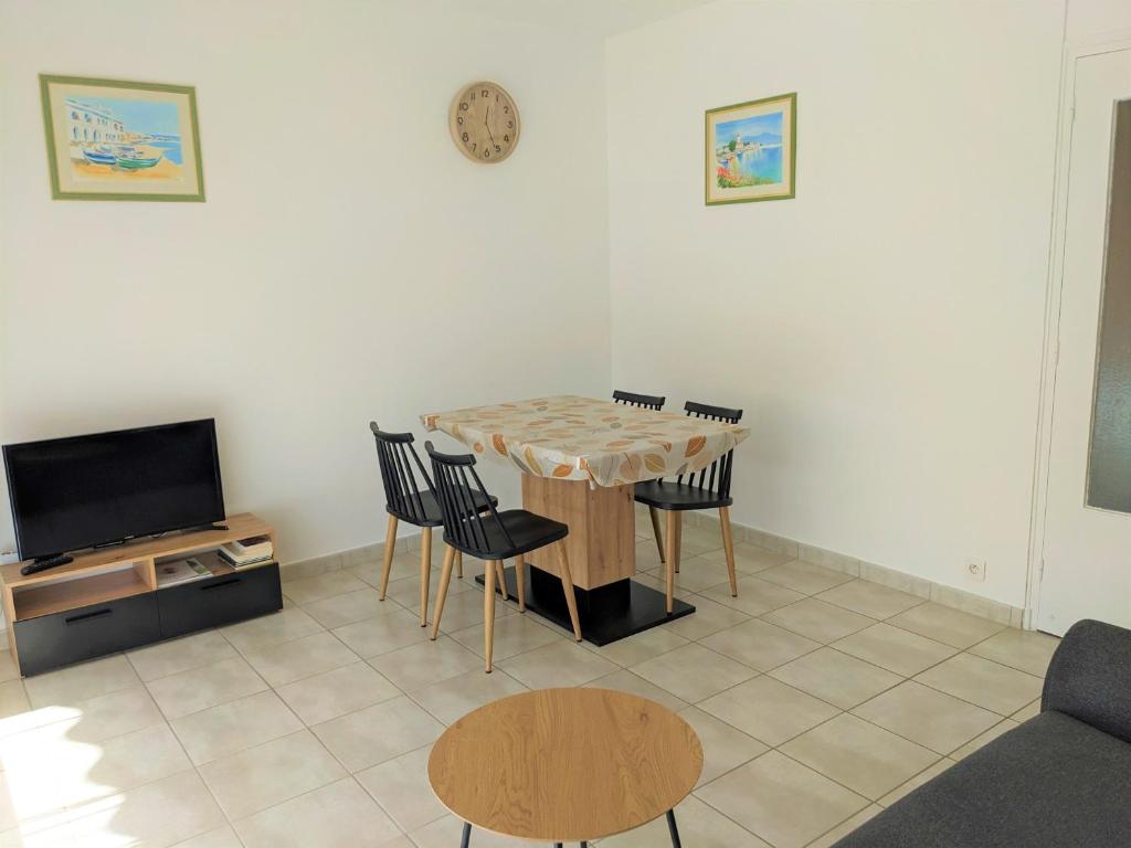 ein Wohnzimmer mit einem Tisch und Stühlen sowie einem TV in der Unterkunft NOUVEAU Appartement T2 meublé classé, secteur petite Provence in Amélie-les-Bains-Palalda