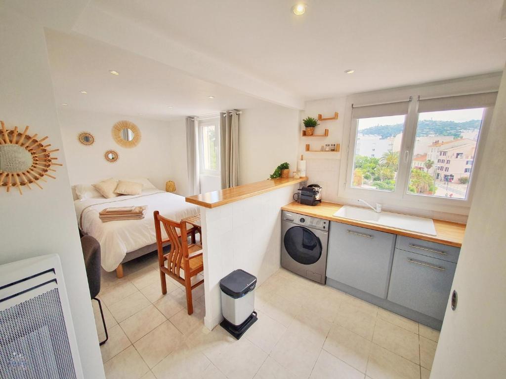 Hotel Studio Cosy & Lumineux *Centre ville Cannes*, a bedroom with a bed and a kitchen with a sink at Studio Cosy & Lumineux *Centre ville Cannes* in Cannes