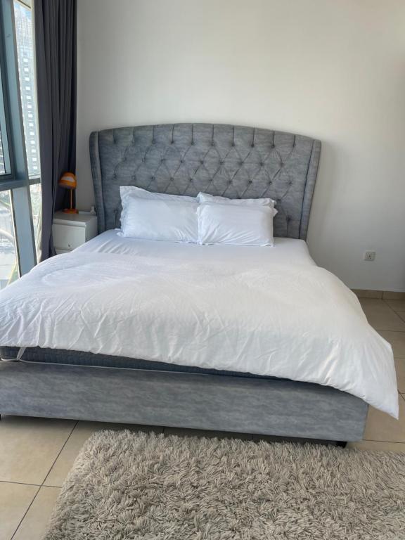uma cama com lençóis brancos e uma cabeceira cinzenta em Bellehomez em Dubai