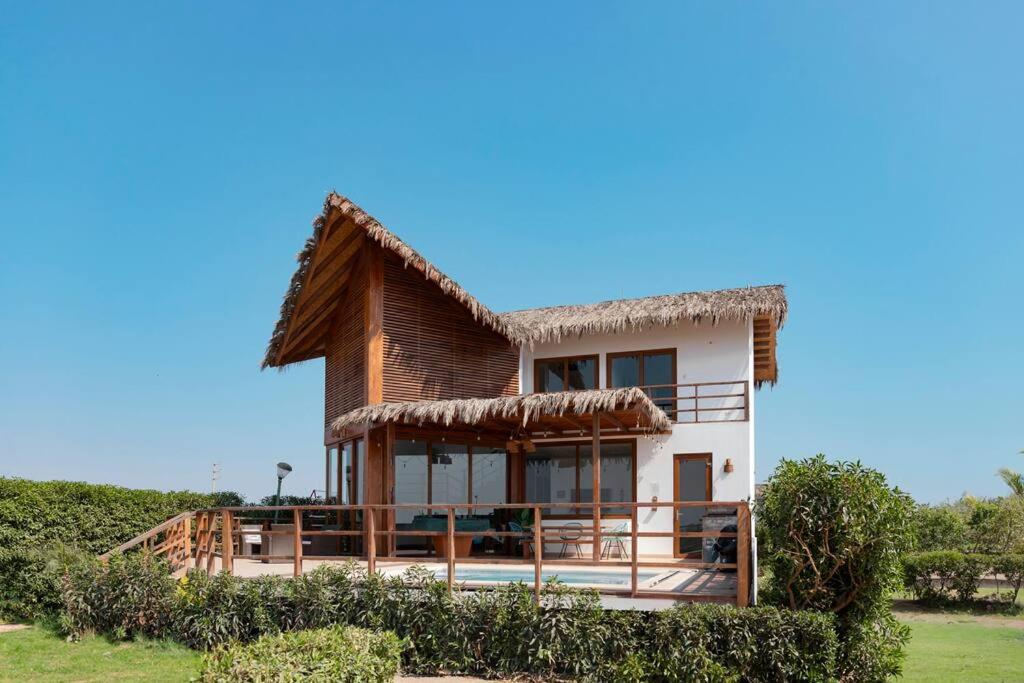 uma villa com telhado de palha numa praia em ZAFIRO CHINCHA® Casa de Lujo Piscina frente al mar em Casa Blanca
