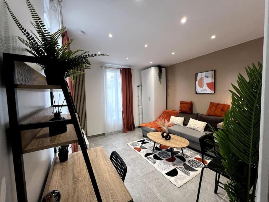een woonkamer met een bank en een tafel bij Le Japandi - Cosyloc Agency - Aux Portes de Paris in Pantin