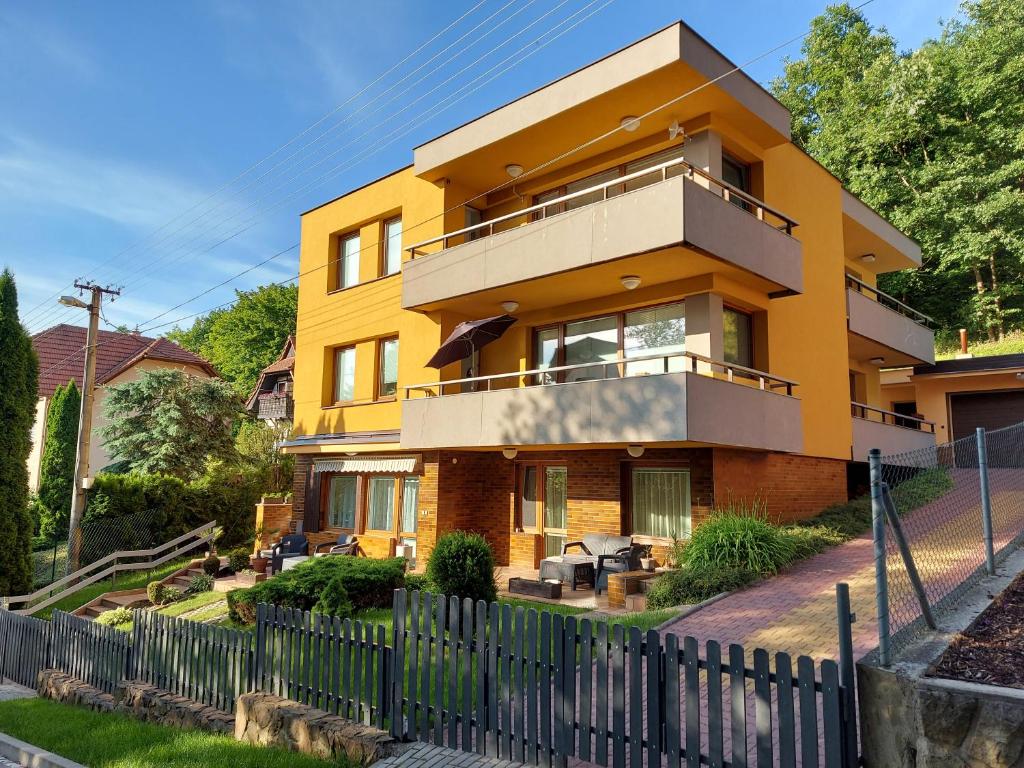 uma casa amarela com uma cerca em frente em Apartmány Luhačovice em Luhačovice