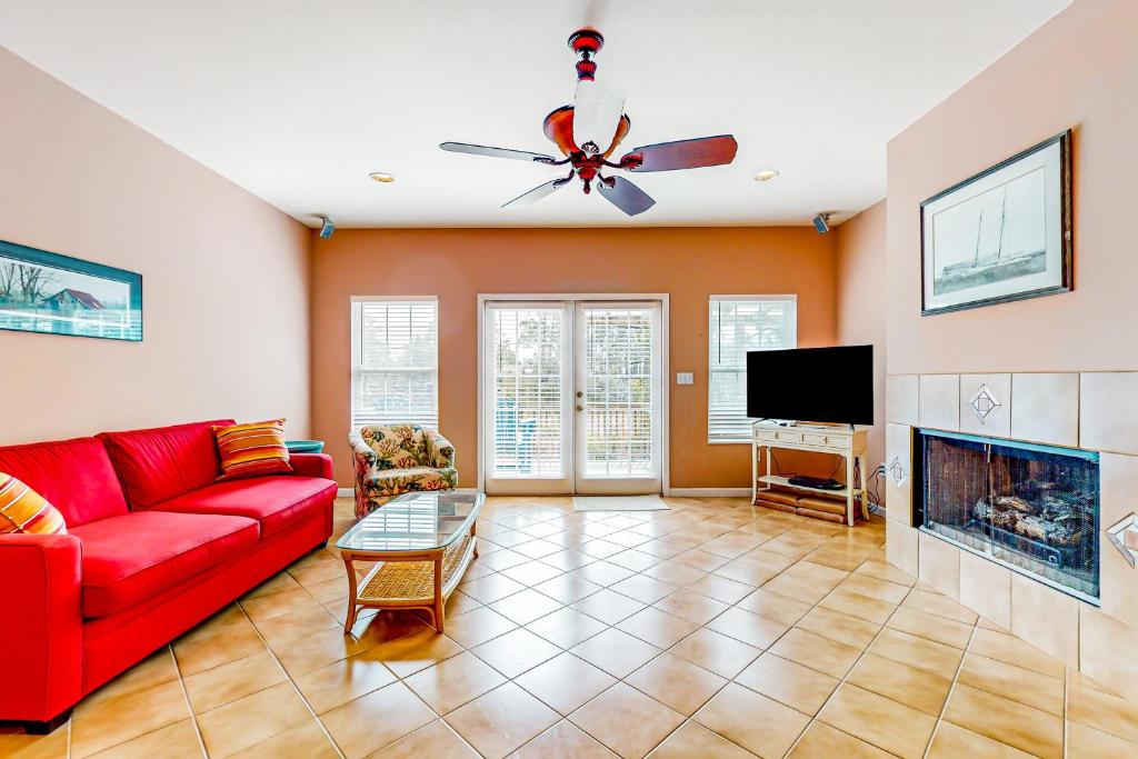 a living room with a red couch and a tv at Sandy Feats in Gulf Highlands