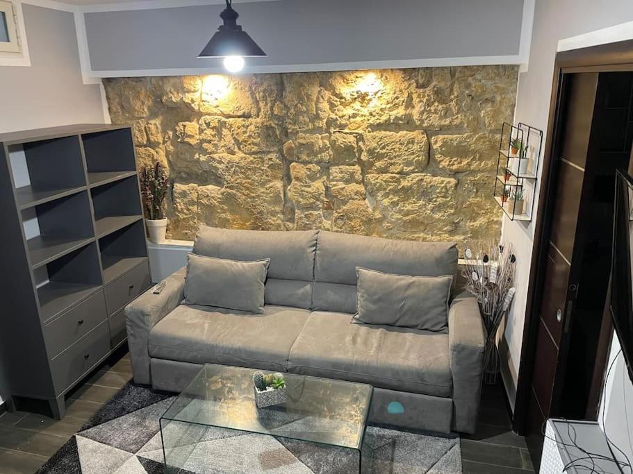 ein Wohnzimmer mit einer Couch und einer Steinwand in der Unterkunft Mrassi in Palermo