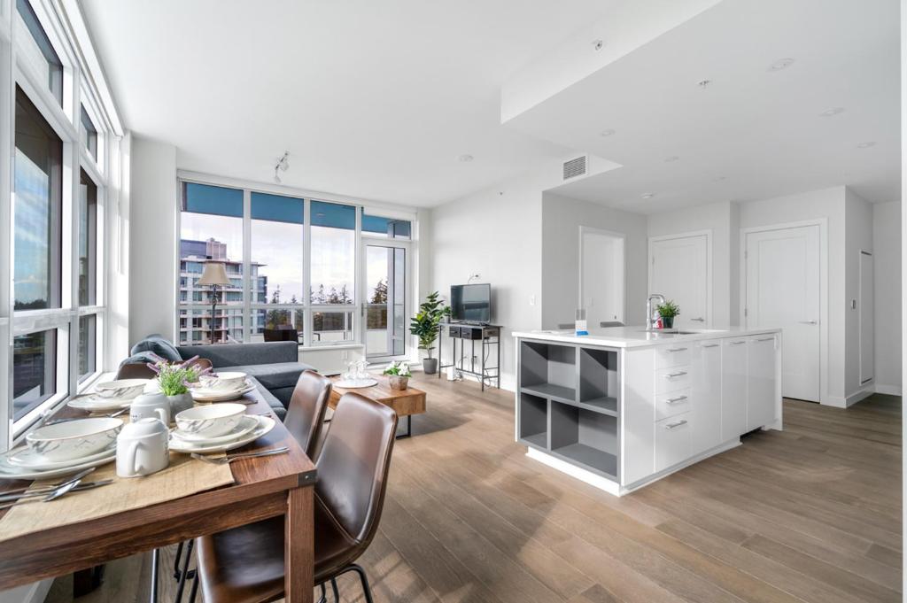 uma cozinha e sala de estar com mesa e cadeiras em Urban Oasis: Stylish Apartment Retreat at UBC em Vancouver