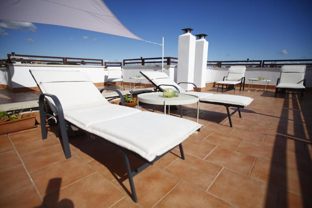 d'un balcon avec des chaises blanches et des tables sur le toit. dans l'établissement Gianicolo House, à Rome