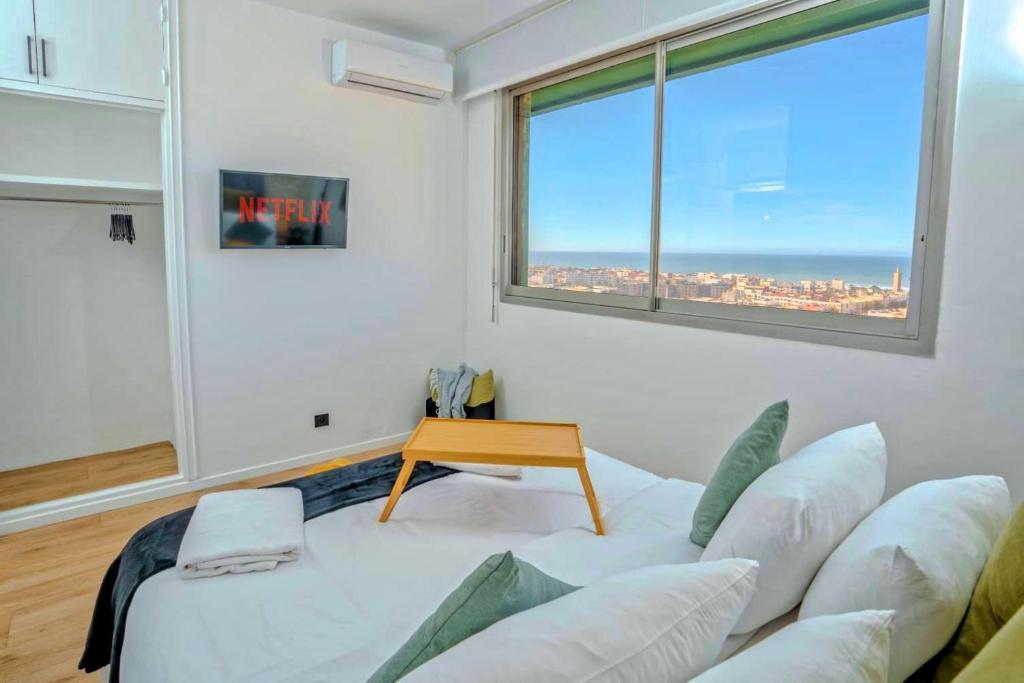 ein Wohnzimmer mit einem weißen Sofa und einem Fenster in der Unterkunft Rabat vue du ciel, majestueux et panoramique centre ville in Rabat