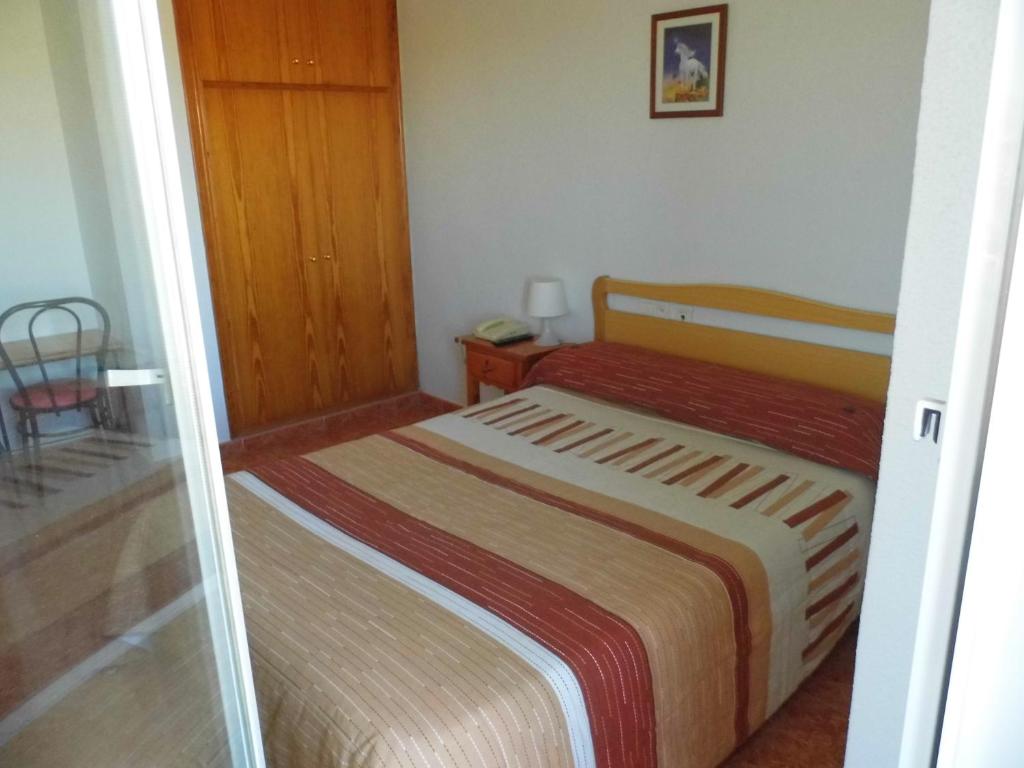 a small bedroom with a bed and a chair at Hotel COSTAS in Fortuna