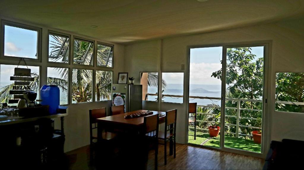 a kitchen with a table and chairs and windows at Cabin de Paulin 1 in Tagaytay