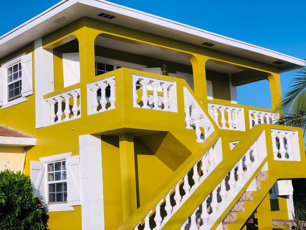 a yellow and white building with a balcony at JB's Cottage in Bottle Creek Settlements