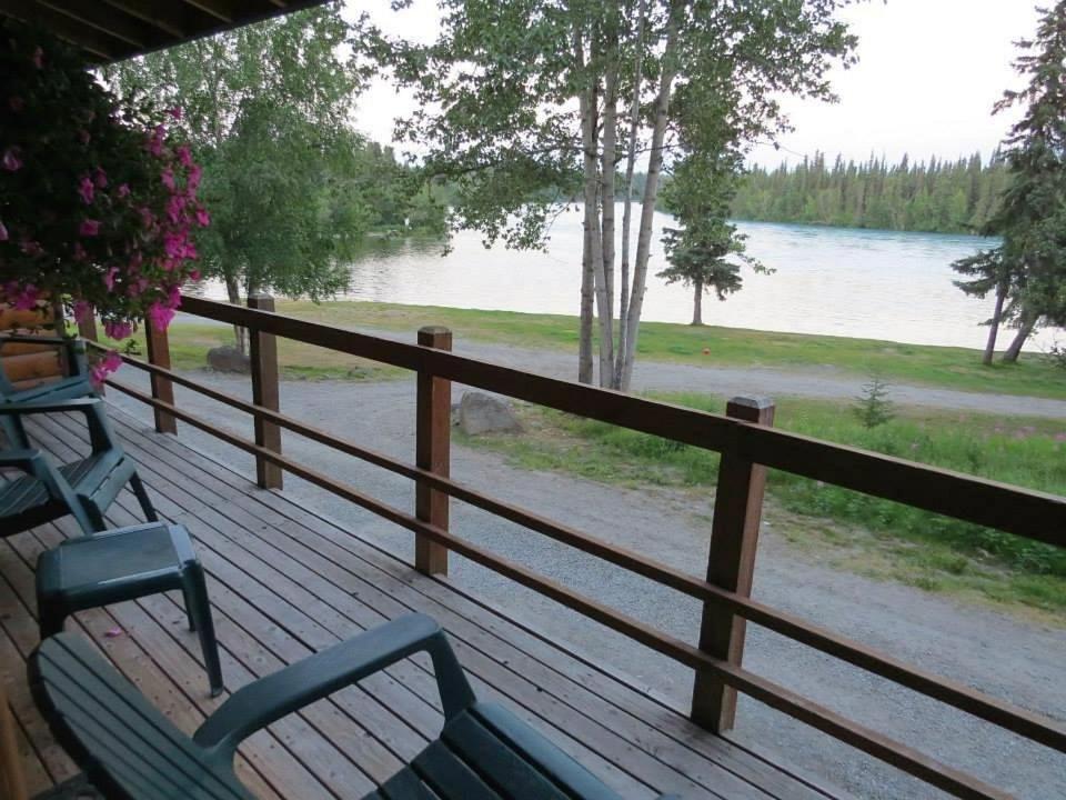 two benches sitting on a deck overlooking a lake at Great Alaska Adventure Lodge in Sterling
