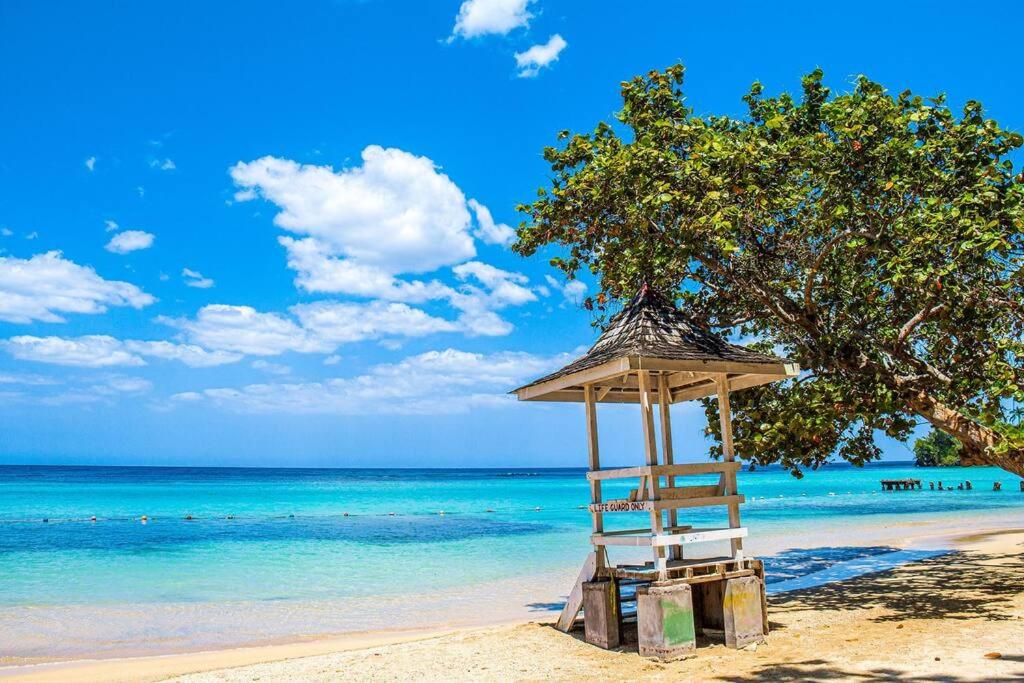 a lifeguard stand on a beach with a tree at Sun Haven Villa in Discovery Bay, St. Ann in Discovery Bay