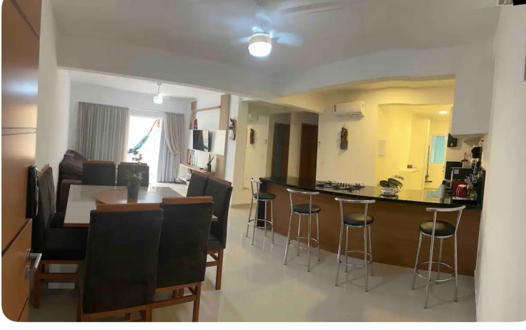 a living room with a kitchen and a bar with stools at Apartamento encantador próximo a Praia Brava in Matinhos