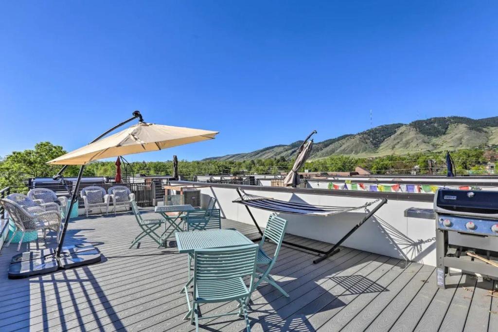 una terraza con sillas, mesas y sombrilla en Golden Rooftop w Mountain Views - Walk to DT Golden School of Mines Close to Red Rocks, en Golden