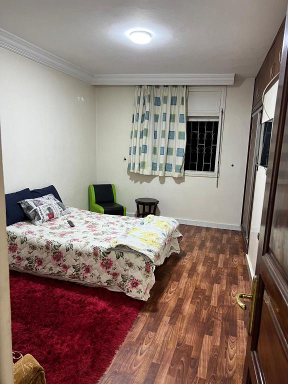 a bedroom with a bed and a chair and a window at Appartement calme au centre ville in Casablanca