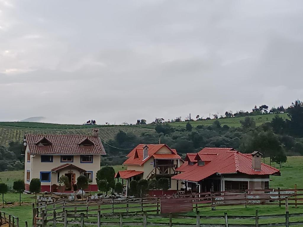 Chaupi的住宿－Refugio de Montaña Huerta Sacha，一群在田野上拥有红色屋顶的房屋