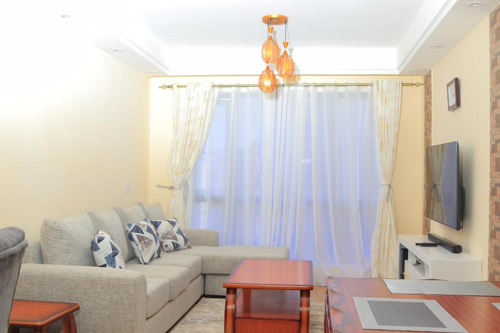 a living room with a couch and a tv at Spacious, beautiful, elegant, with natural light 1 bedroom Apartment in Nairobi