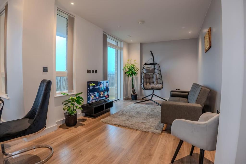 uma sala de estar com uma televisão e um sofá e cadeiras em 2 Bedroom Flat near Stanmore Station em Stanmore