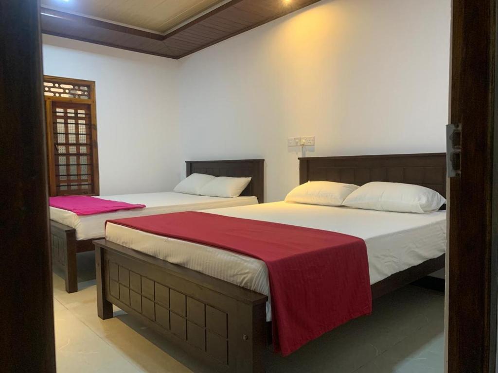 a bedroom with two beds with red sheets at Nesan’s villa in Trincomalee