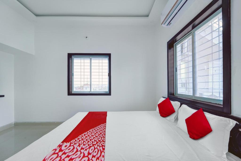 a white room with a bed with red pillows at Flagship Hotel White House in Rānchī